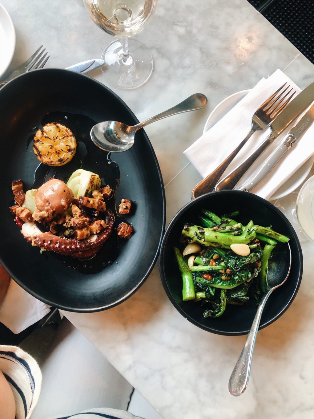 Overhead view of grilled octopus and chinese broccoli on the marble bar top at Joule Restaurant in Seattle.