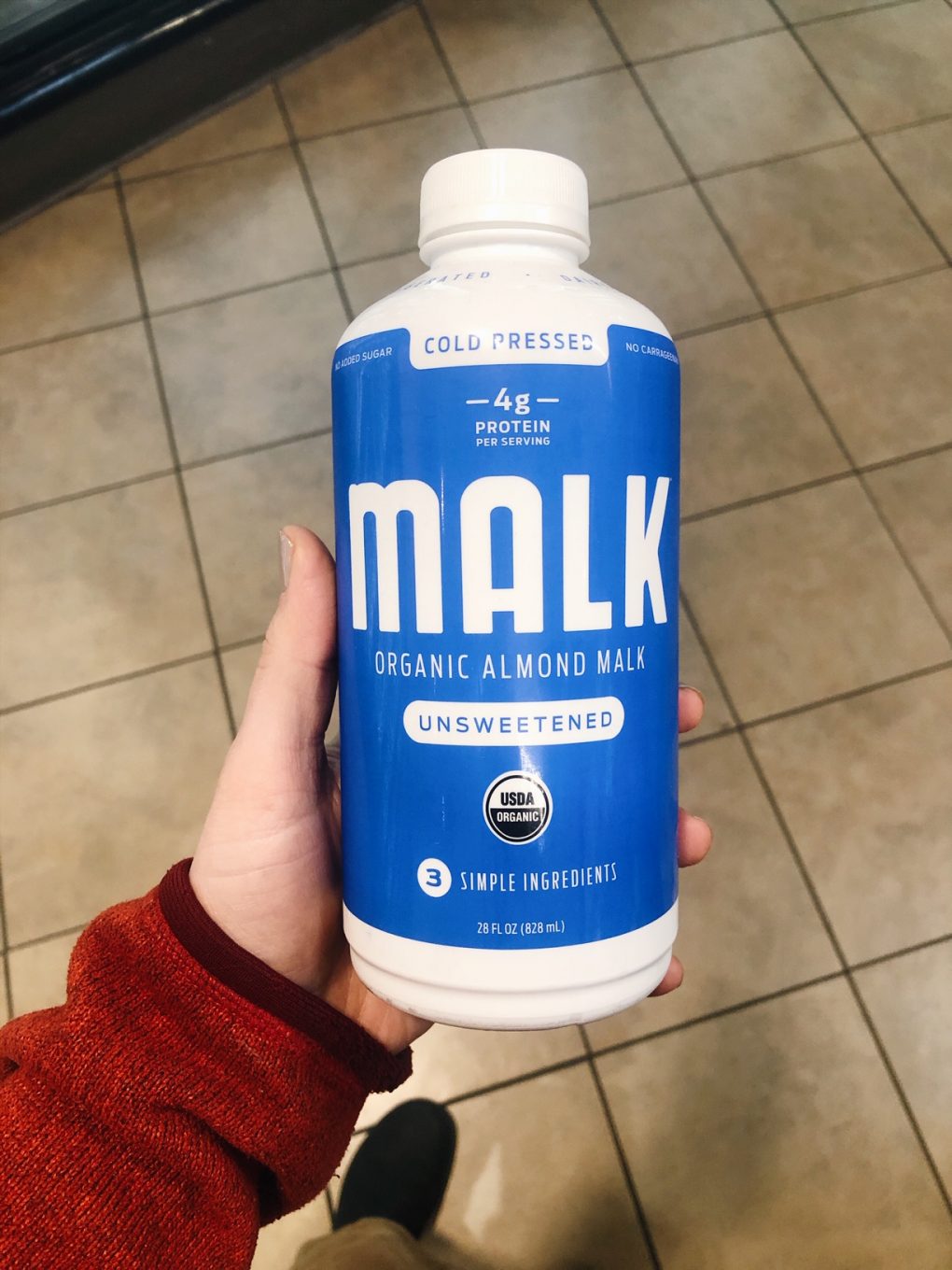 Holding a bottle of malk organics almond milk in the grocery store