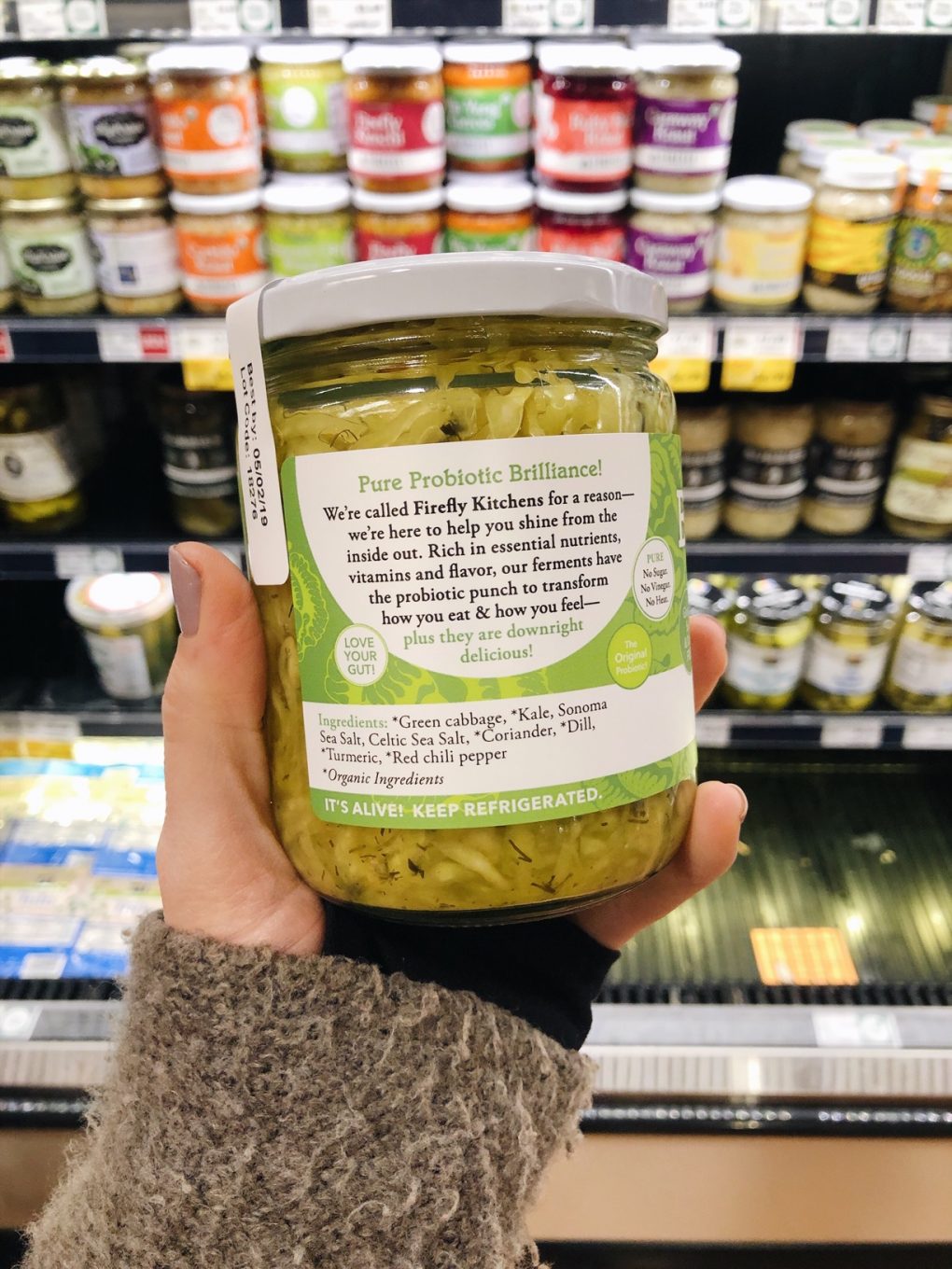 Holding a jar of emerald city sauerkraut at the grocery store with ingredients showing