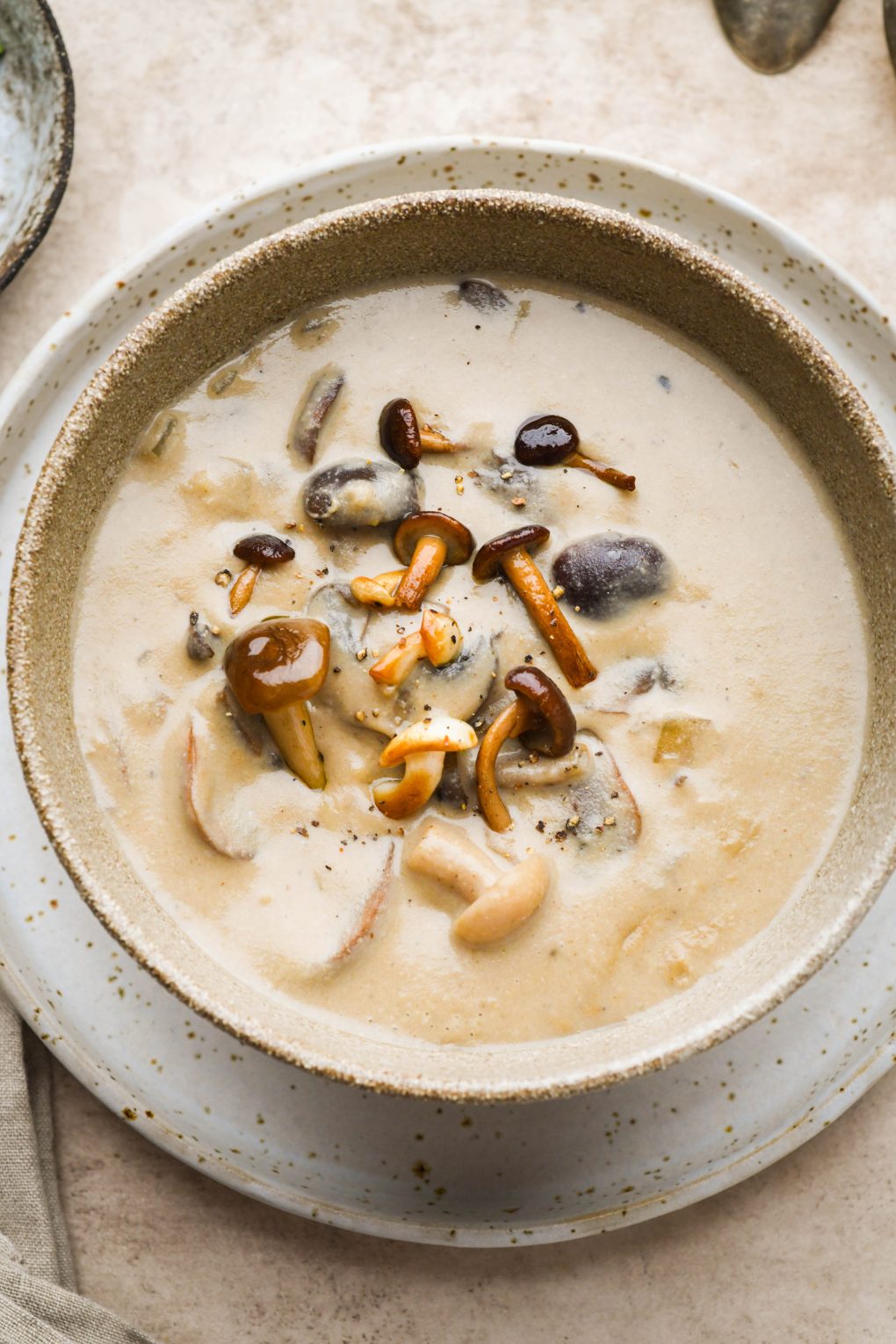 Super creamy homemade cream of mushroom soup in a rustic brown ceramic bowl. Topped with sautéed mushrooms.