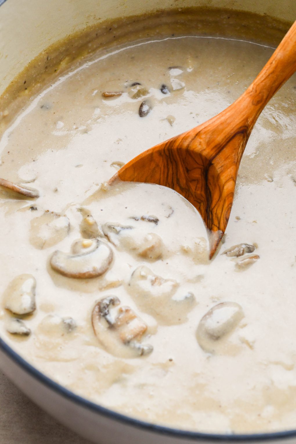 Step by step images for how to make homemade cream of mushroom soup: Creamy blended soup in a large white ceramic soup pot.