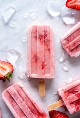Four scattered strawberry and coconut milk popsicle on a white background