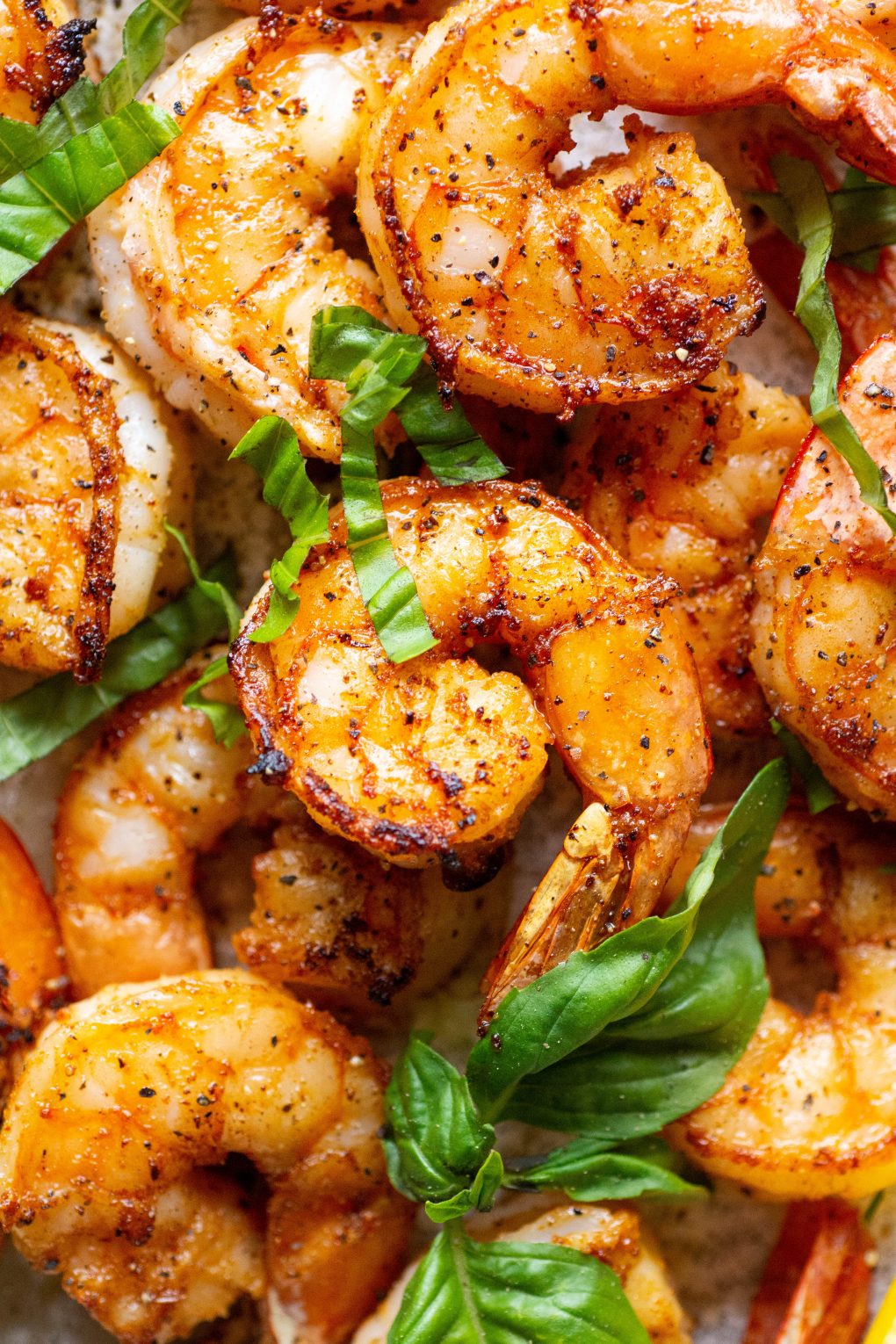 Close up shot of seared shrimp topped with fresh basil