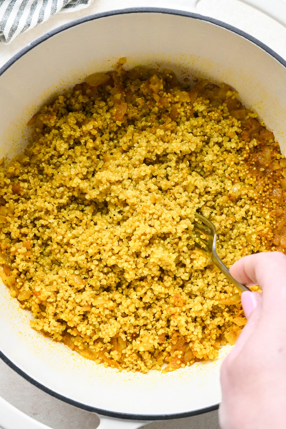 How to make curried quinoa pilaf: Fluffing cooked quinoa with a fork.