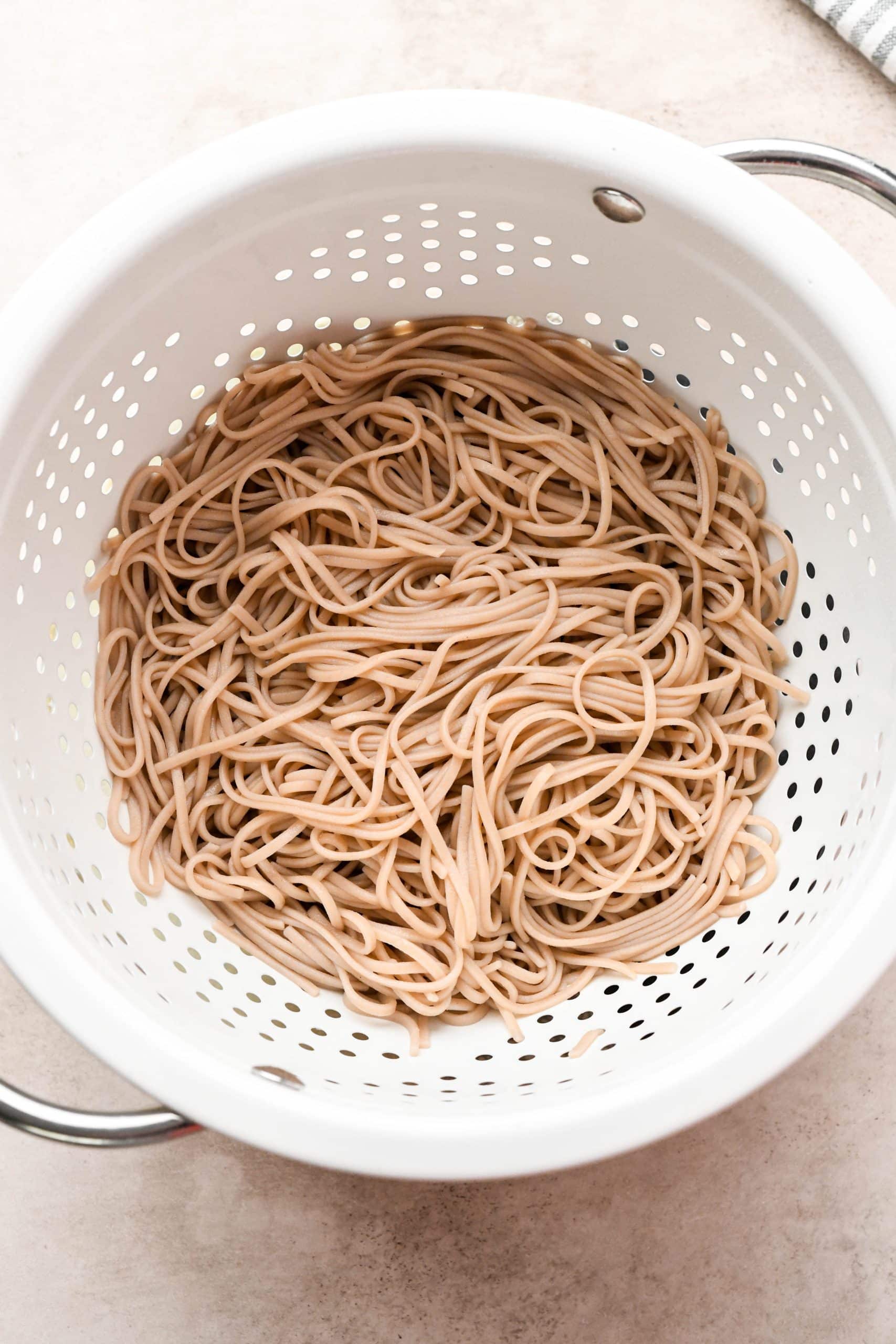 How to make soba noodle stir fry: Cooked soba noodles in a colander.
