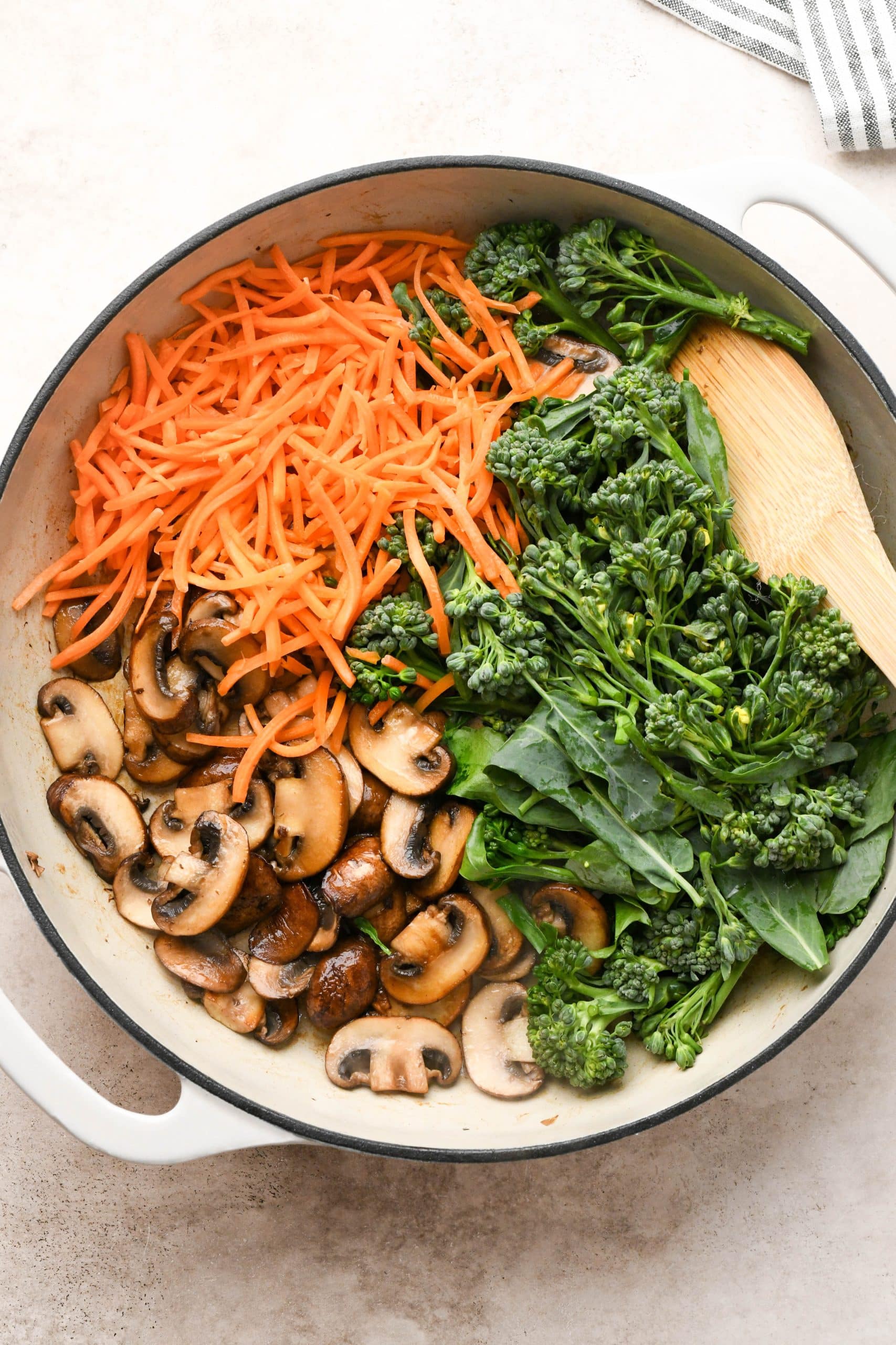 How to make soba noodle stir fry: Seared mushrooms in a skillet with raw broccoli florets and raw shredded carrots.