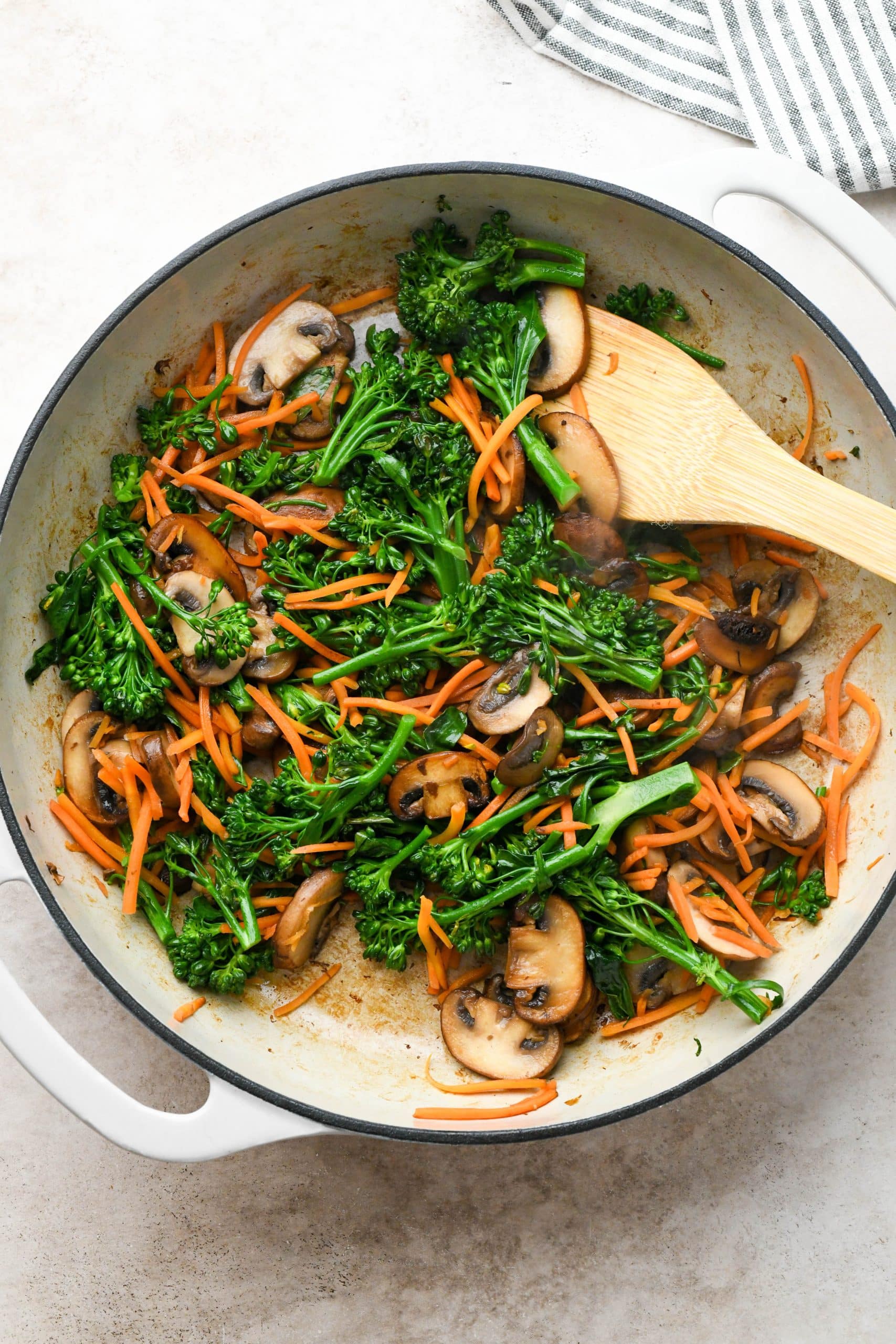 How to make soba noodle stir fry: Seared mushrooms with cooked broccoli and cooked shredded carrots in a skillet.