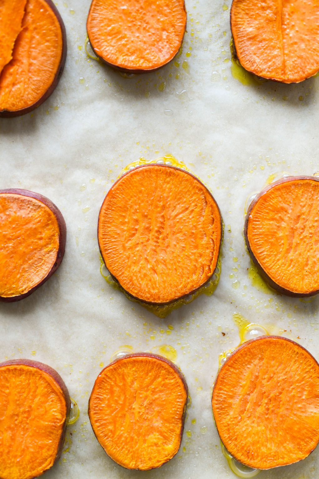 Overhead shot of roasted sweet potato rounds on a parchment lined baking sheet.