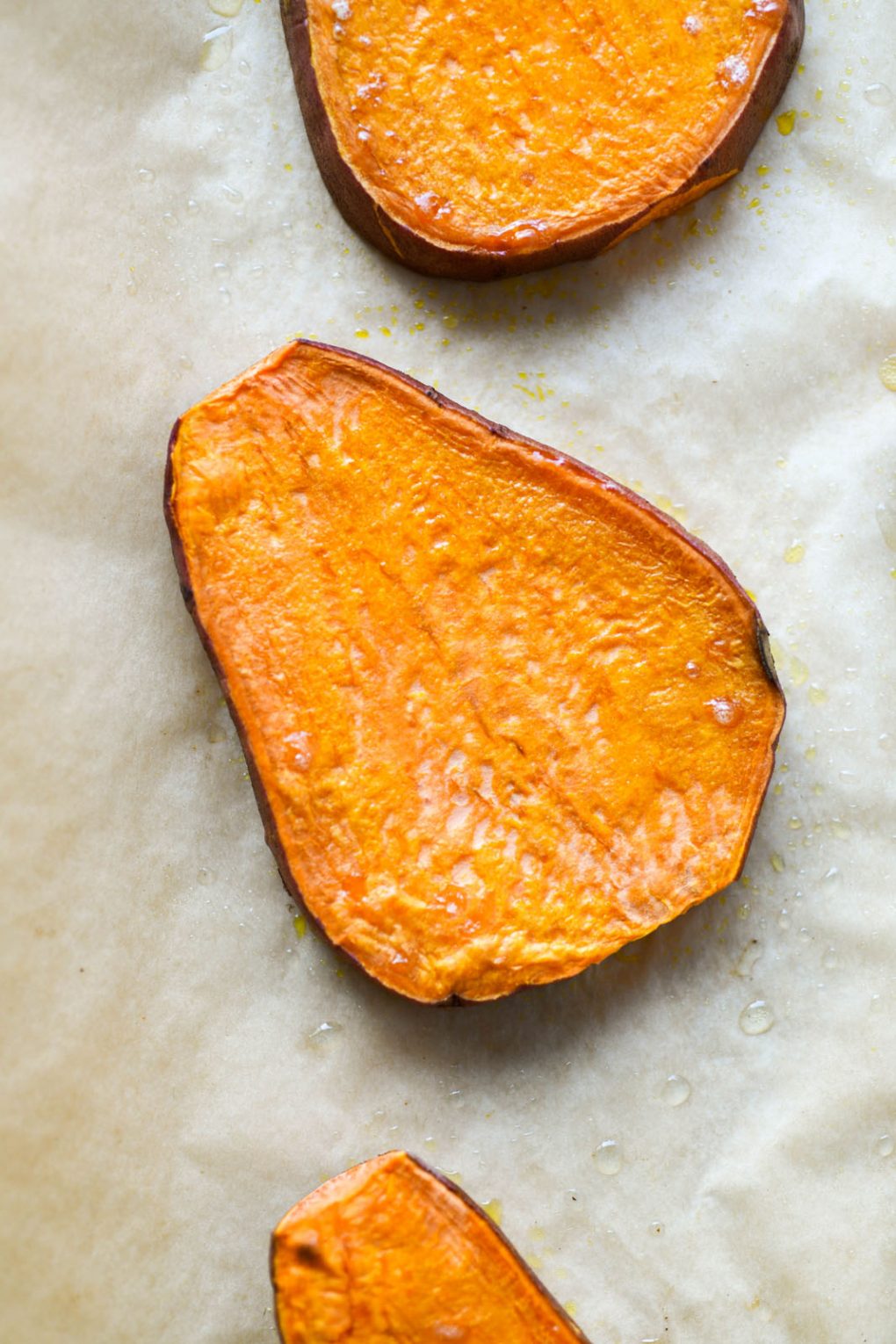 Close up overhead shot of a roasted sweet potato plan on a parchment lined baking sheet.