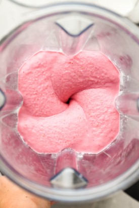 Overhead shot of the interior of a blender container blending a thick and creamy strawberry banana smoothie.