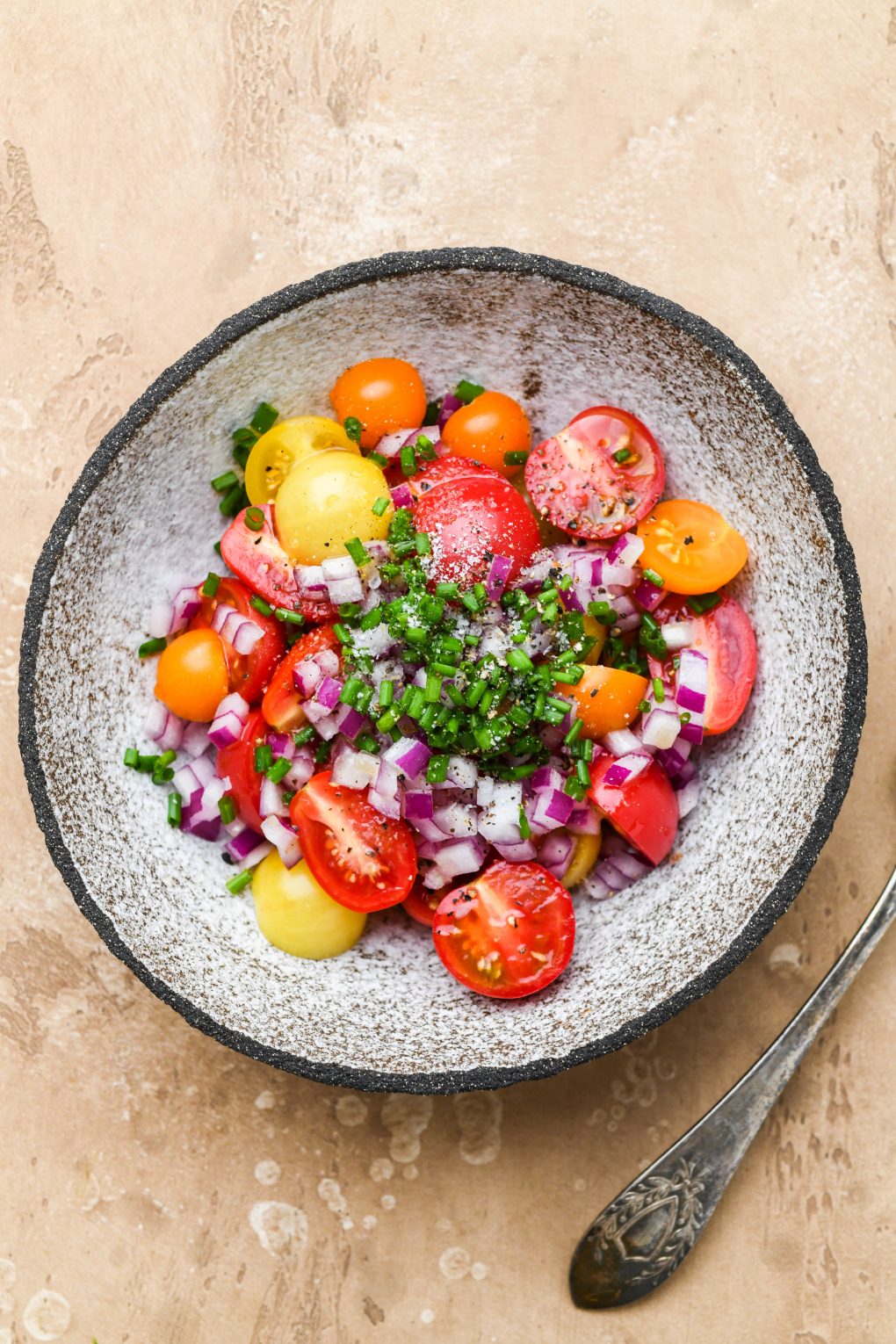 A small textured bowl with the ingredients for the cherry tomato salad garnish before mixing.