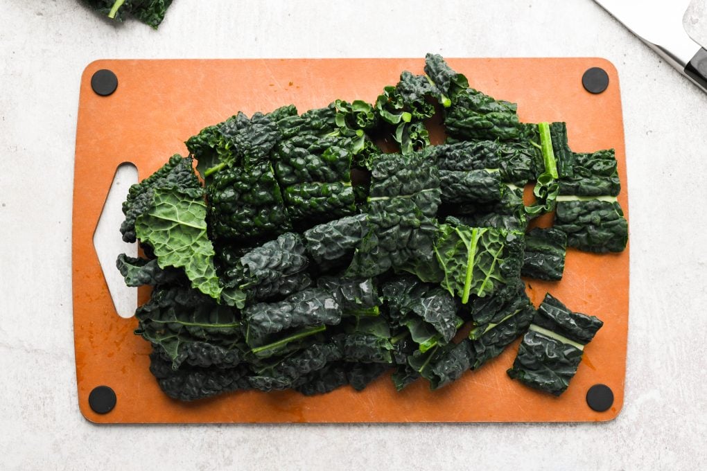 Kale leaves on a cutting board, cut into bit sized pieces.