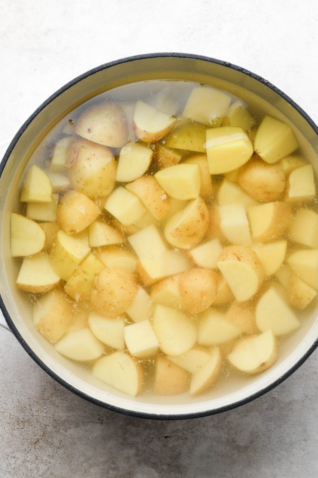Photos showing how to make Whole30 mashed potatoes - Potatoes in a large pot of water.