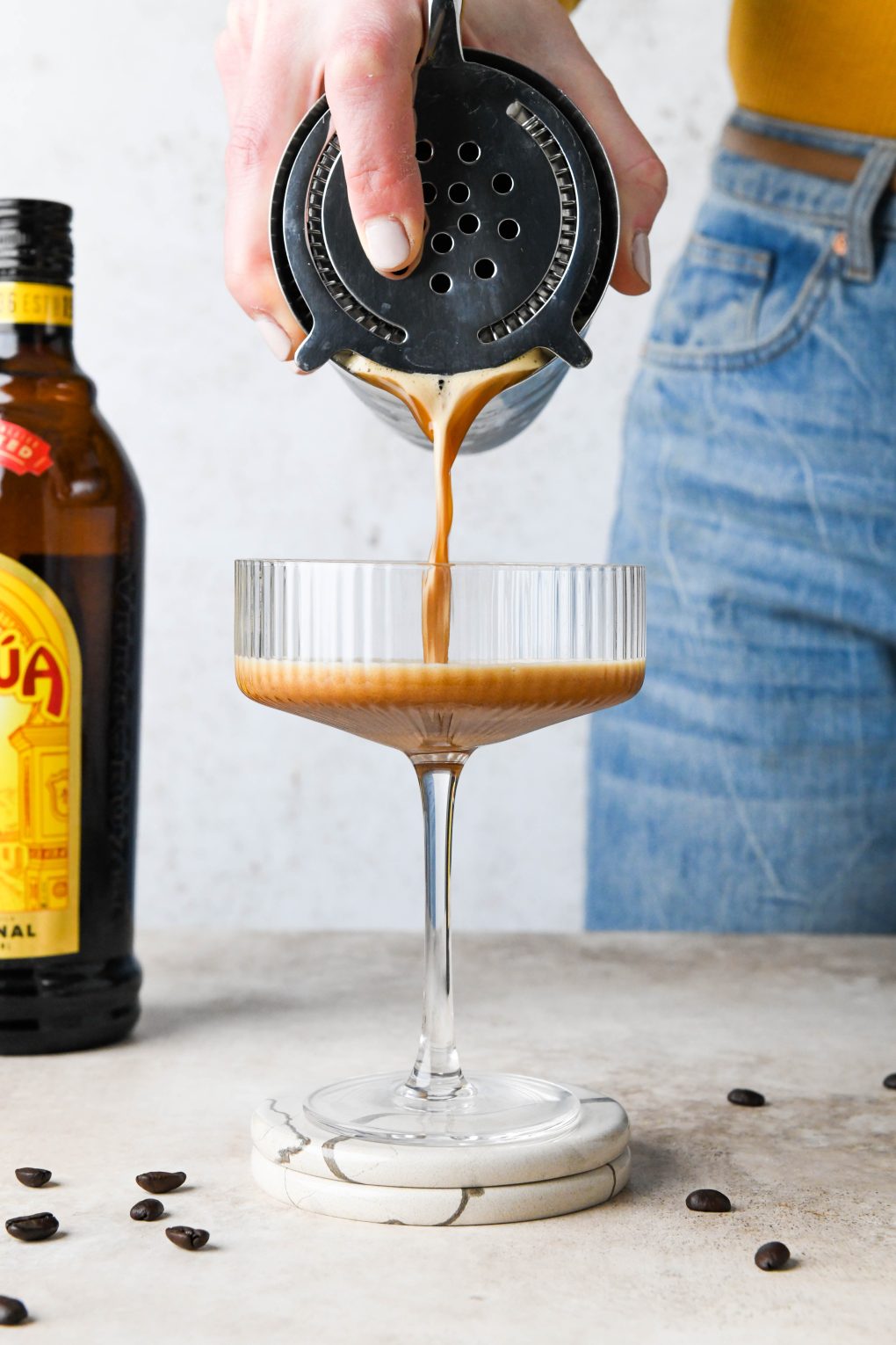 How to make an espresso martini: Starting to pour martini into a coupe glass.