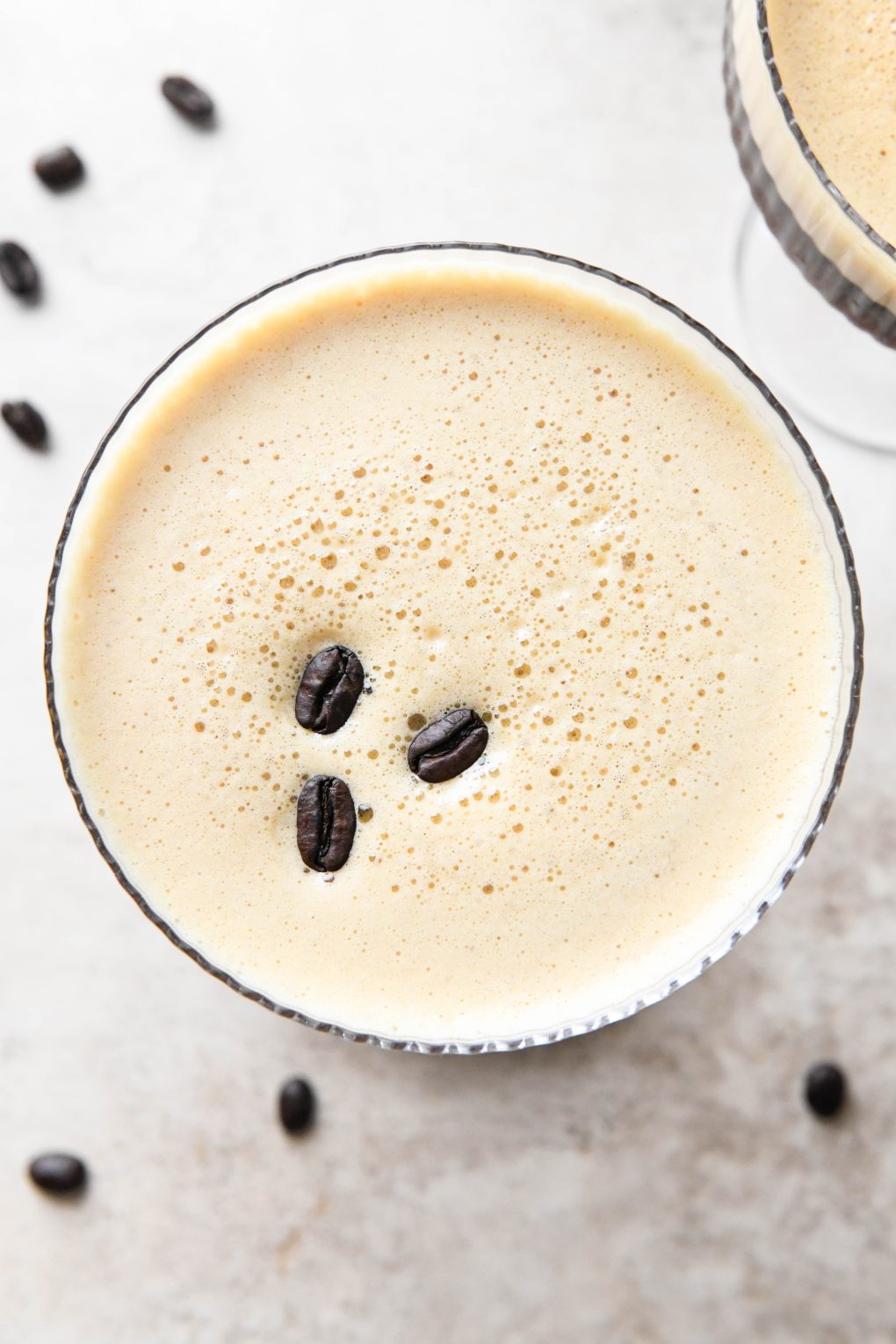 Overhead shot of a foamy espresso martini with 3 coffee beans on top.
