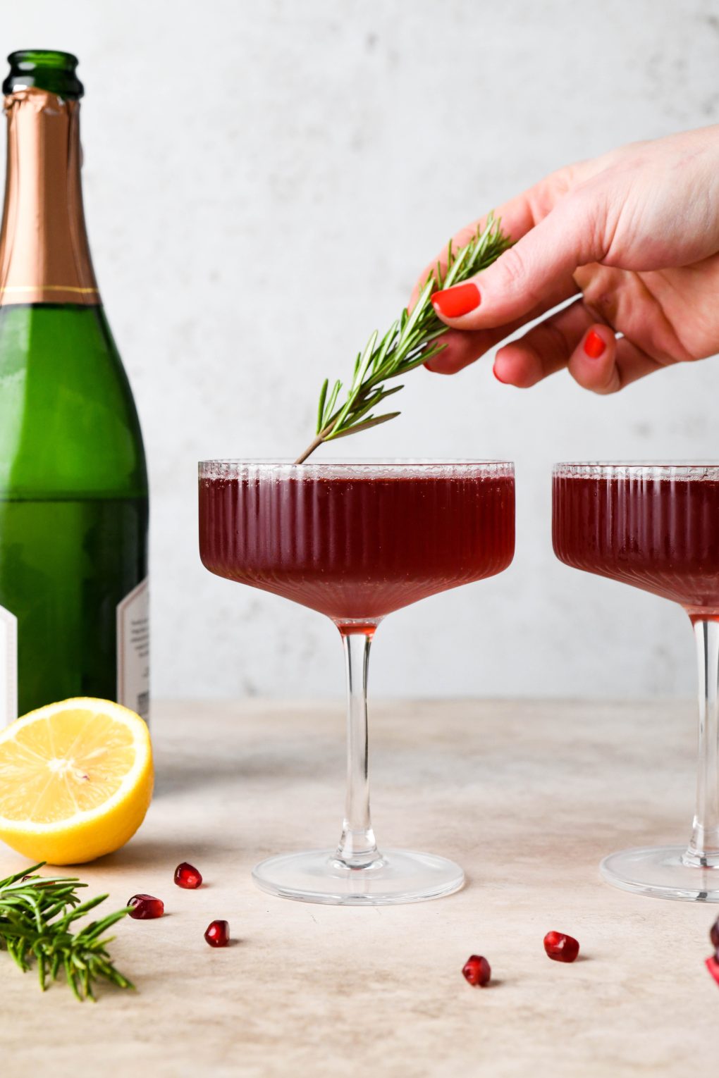 How to make Festive Pomegranate Champagne Cocktail: Topping the cocktail with a sprig of rosemary