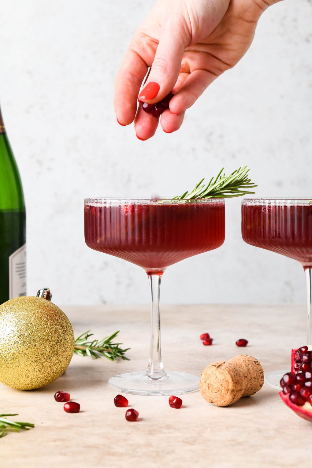 How to make Festive Pomegranate Champagne Cocktail: Dropping pomegranate seeds into the cocktail