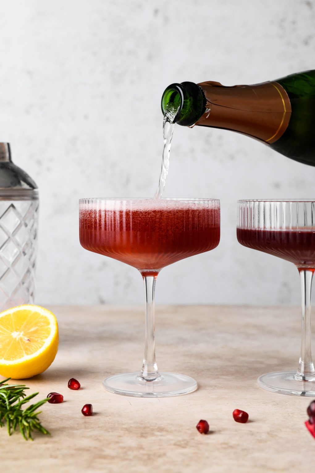 How to make Festive Pomegranate Champagne Cocktail: Pouring champagne into the champagne coupes