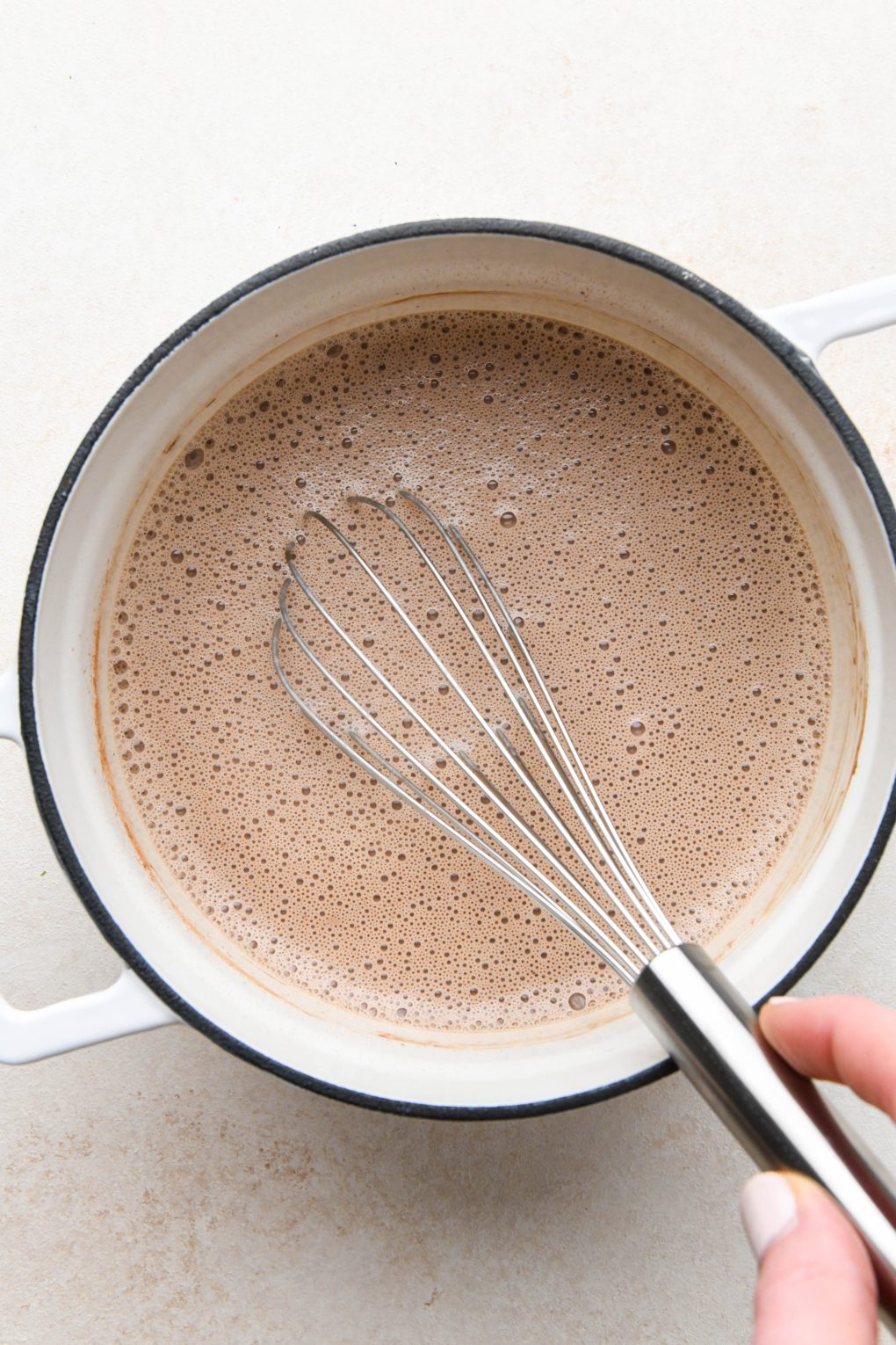 How to make peppermint hot chocolate. Milk, extracts, and cacao powder whisked together in small sauce pan.