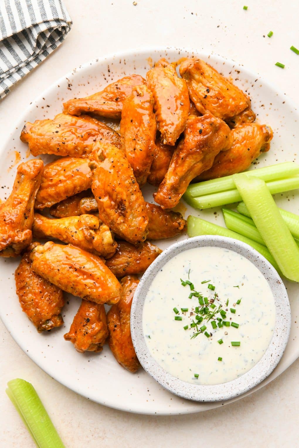 Crispy Baked Buffalo Chicken Wings on a speckled platter with celery sticks and a small bowl of creamy ranch dressing.