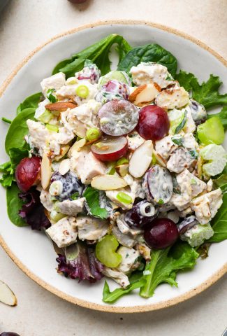 Easy Chicken Salad with Grapes and Almonds on a bed of lettuce on a light colored ceramic plate