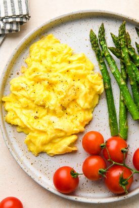 Whole30 breakfast on a speckled plate: Scrambled eggs, roasted asparagus, and cherry tomatoes