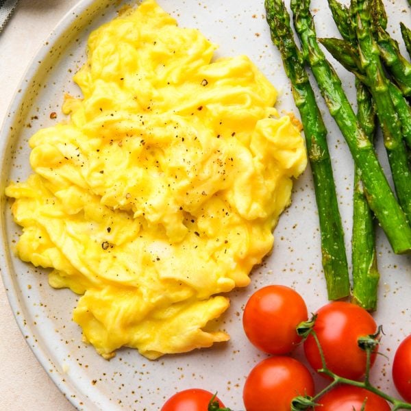 Whole30 breakfast on a speckled plate: Scrambled eggs, roasted asparagus, and cherry tomatoes