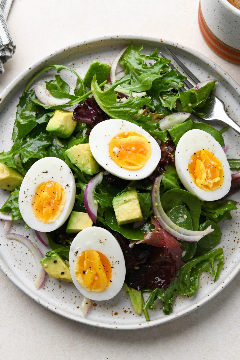 Hard boiled eggs over a simple green salad with avocado.