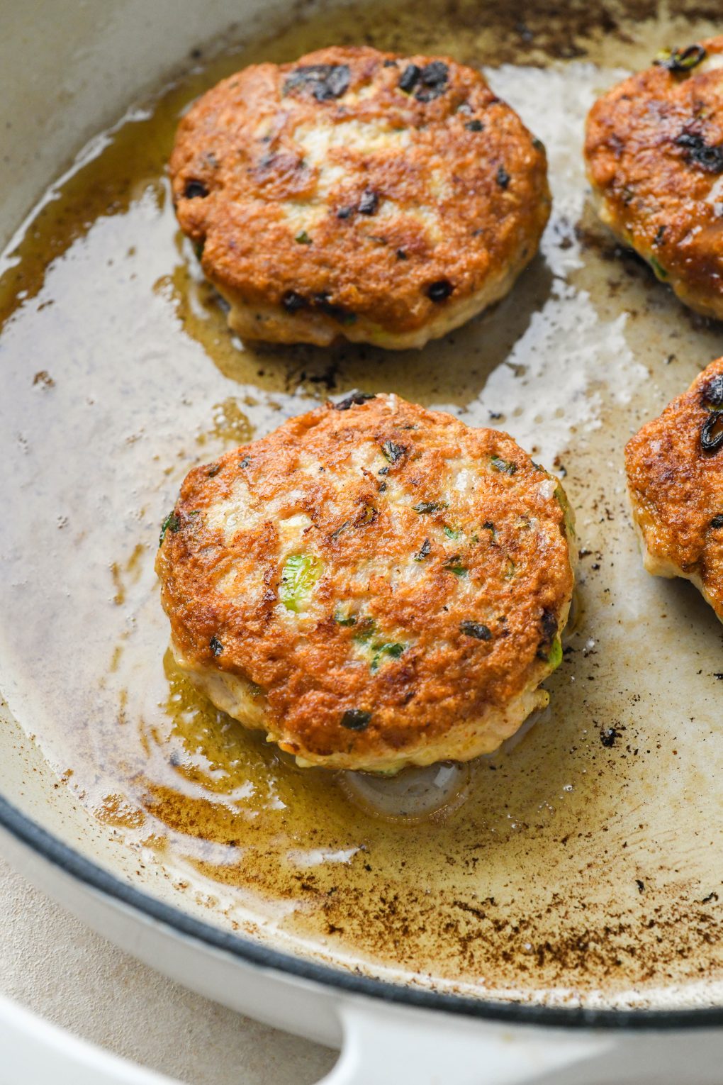 How to make healthy chicken patties: Patties frying in a skillet.