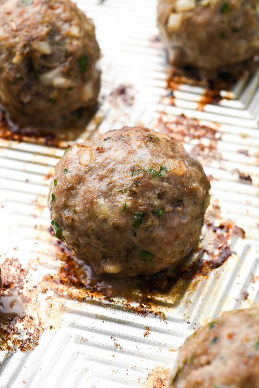 Close up of a baked meatball on a baking sheet.