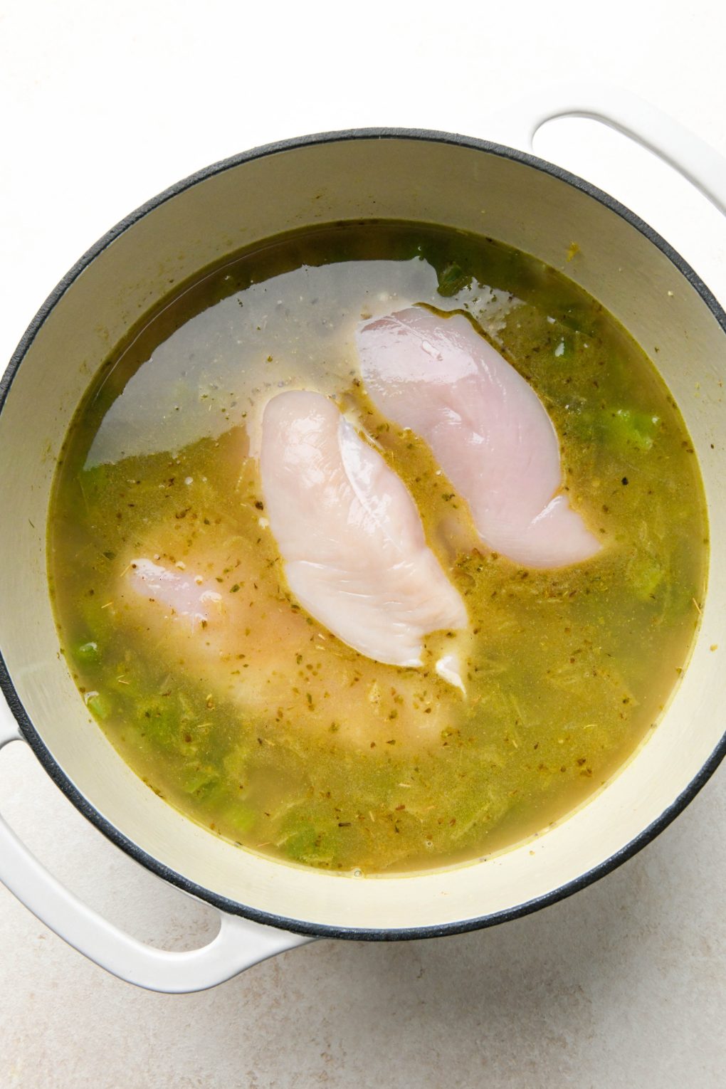 How to make Whole30 White Chicken Chili: Broth and boneless skinless chicken breasts added.