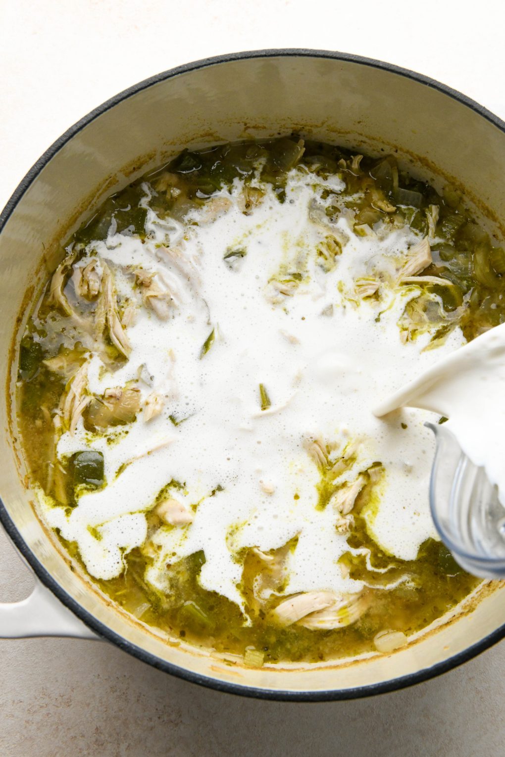 How to make Whole30 White Chicken Chili: Cashew cream being poured into the simmered chili.