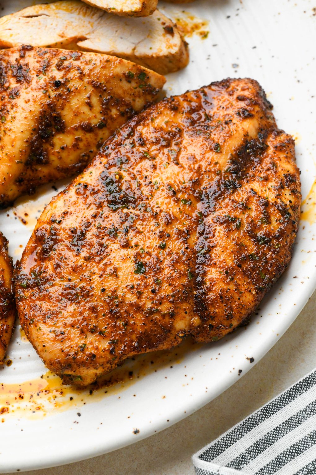 Close up of a perfectly cooked baked chicken breast on a light colored platter.