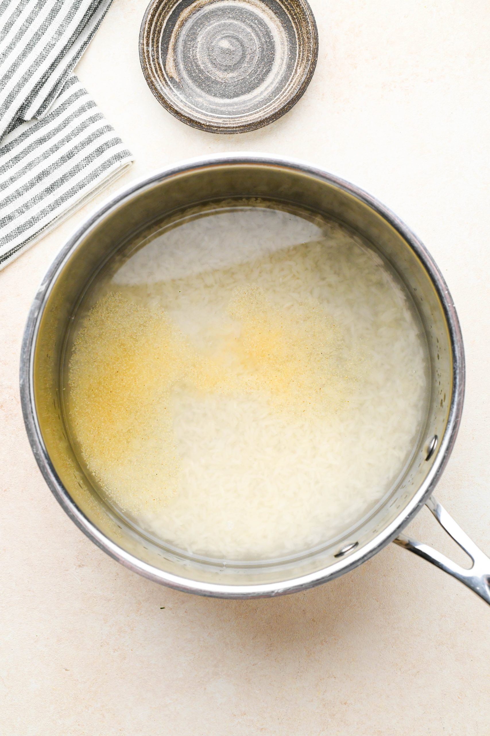 How to make cilantro lime rice: Rice in sauce pan with water, kosher salt, and garlic powder.