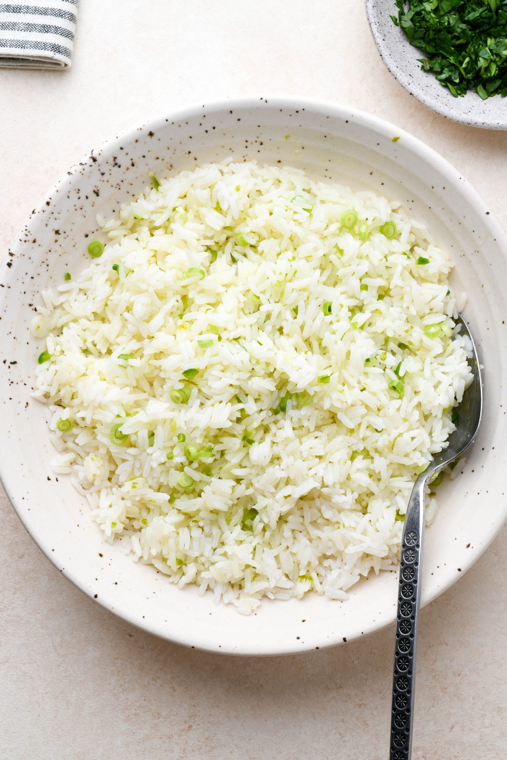 How to make cilantro lime rice: White rice in a large bowl mixed together with olive oil and lime mixture. 