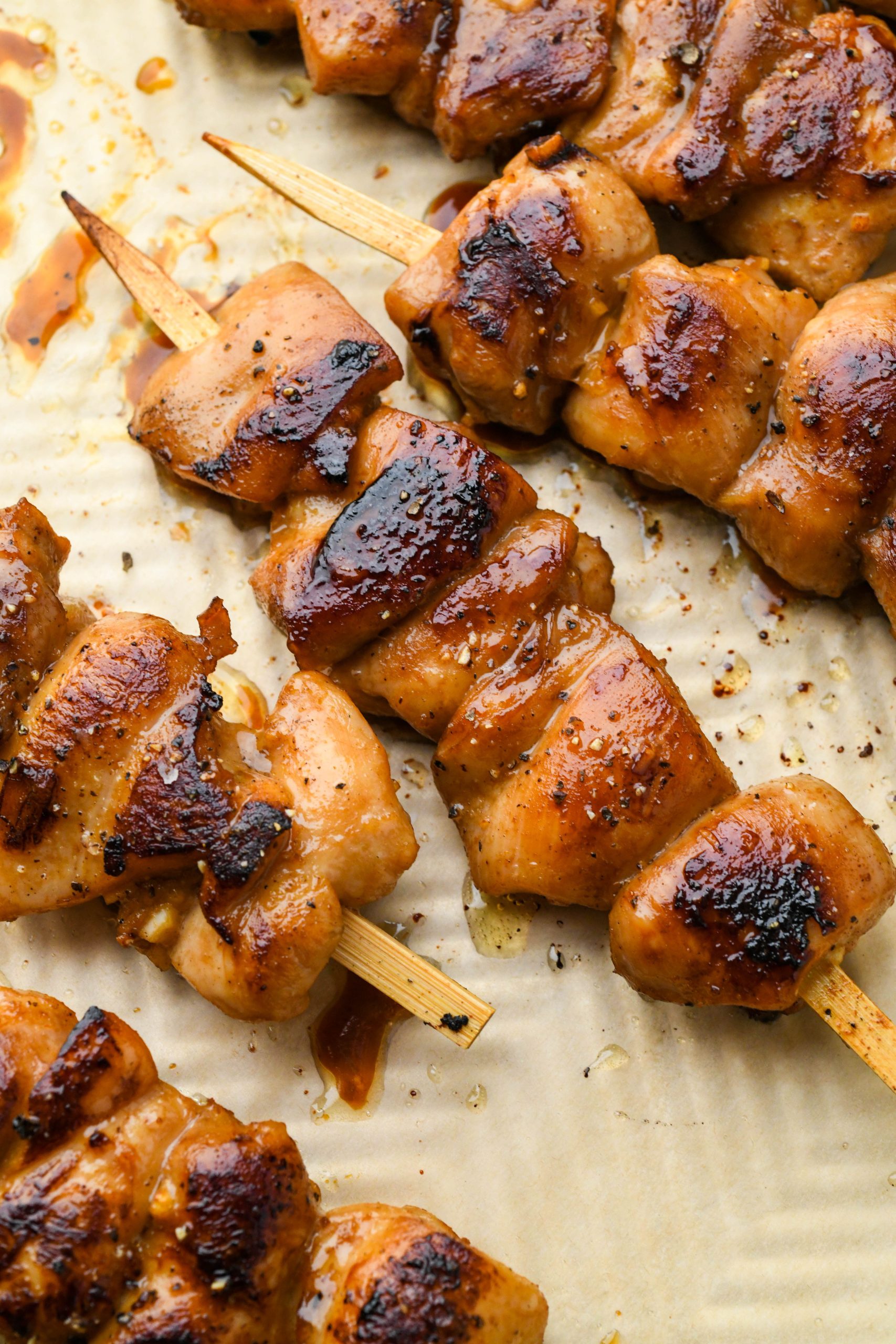 How to make garlic ginger chicken skewers: Chicken skewers on parchment paper straight from the oven.
