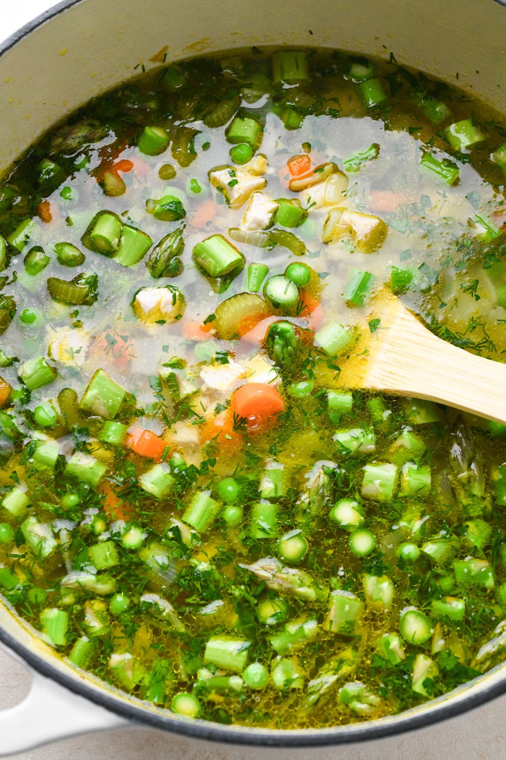 How to make chicken soup with spring vegetables: Soup simmering together in large enameled soup pot.