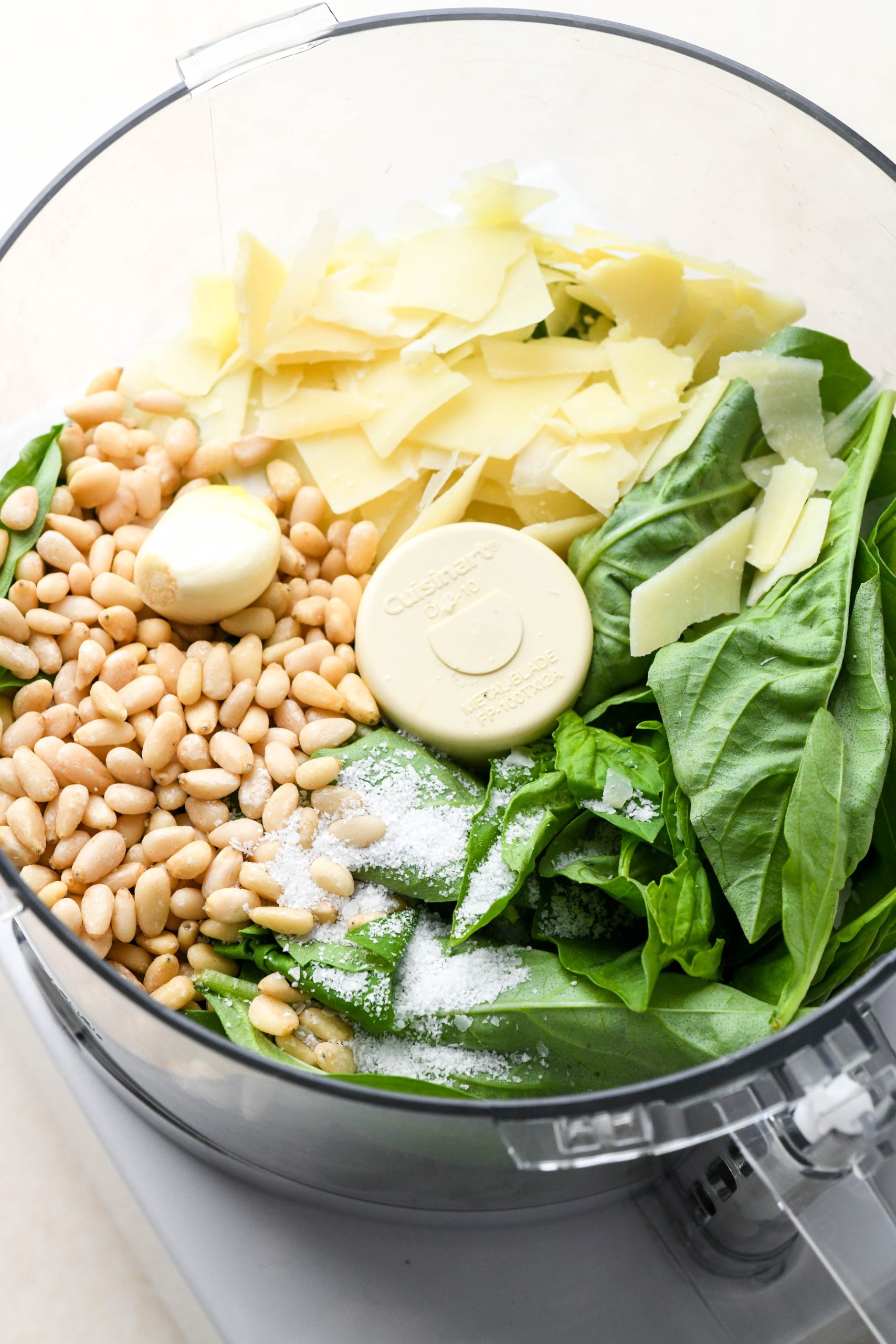 How to make homemade basil pesto: Ingredients for pesto in a food processor container before processing.