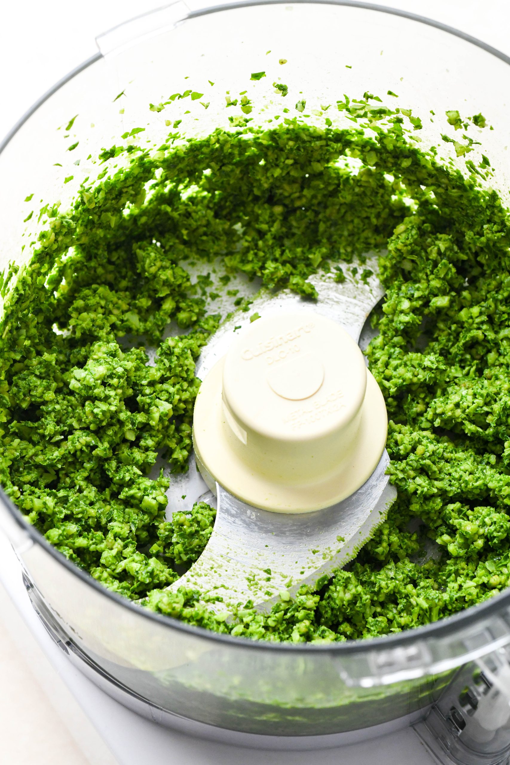 How to make homemade basil pesto: Basil, parmesan, pine nuts, and garlic chopped up in the food processor before adding olive oil.