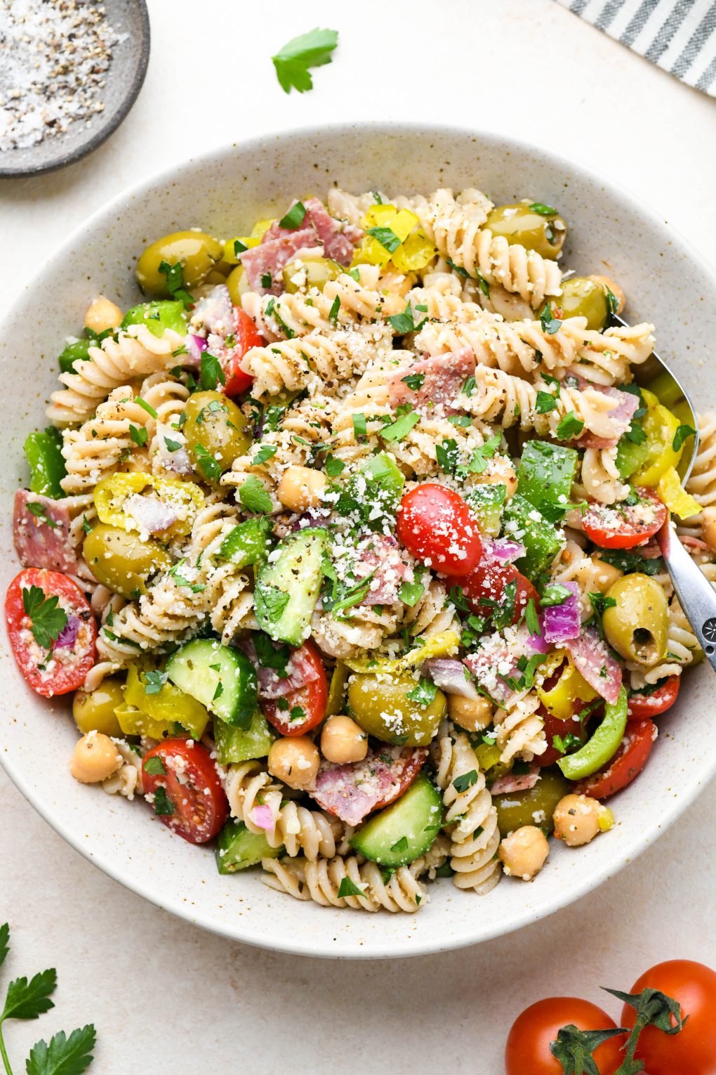 Gluten free Italian pasta salad with fresh ingredients like tomatoes, cucumbers, red onion, olives, herbs, and parmesan cheese.