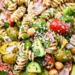 Close up image of easy gluten free Italian pasta salad with fresh ingredients like tomatoes, cucumbers, red onion, olives, herbs, and parmesan cheese.