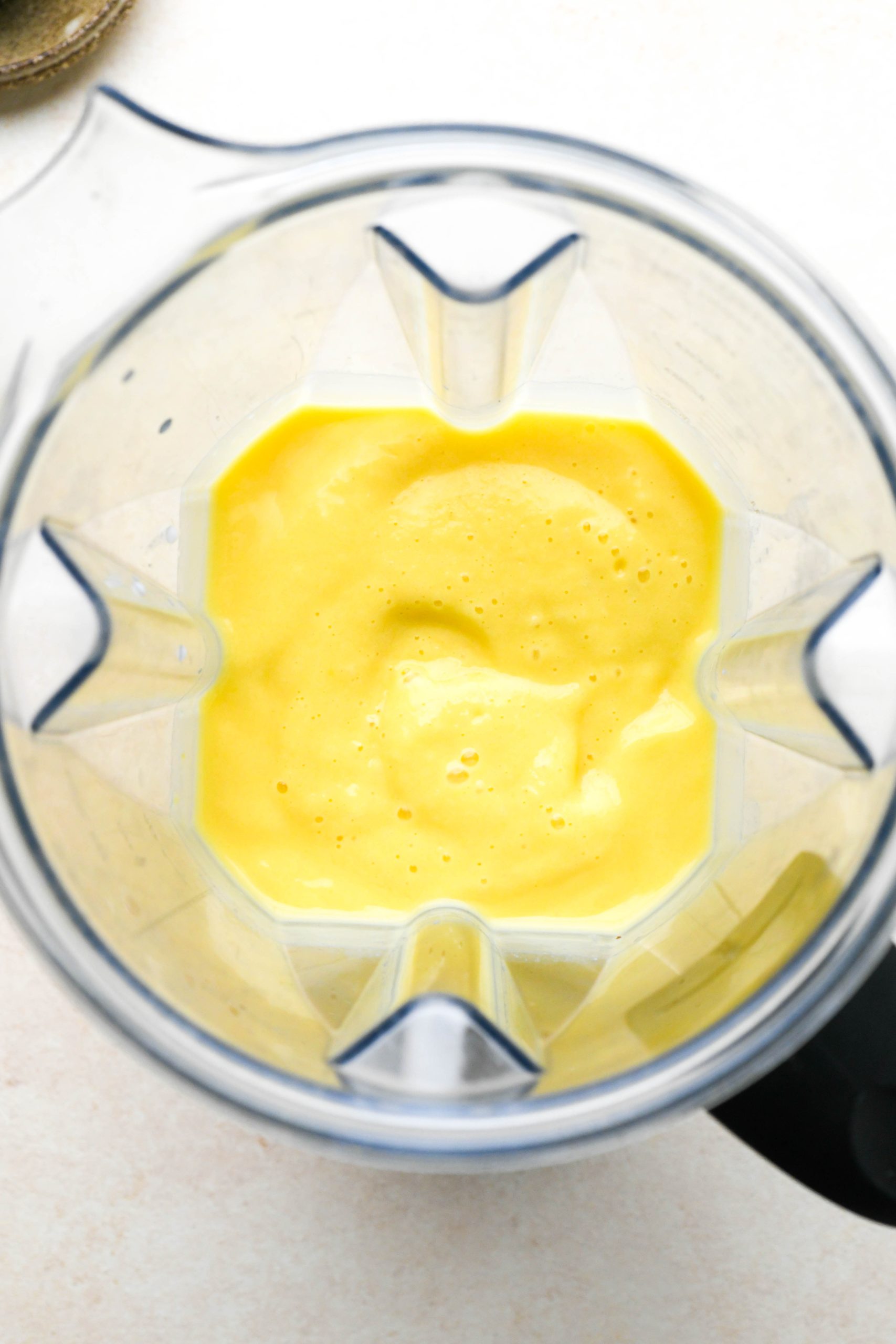 How to make a simple mango smoothie: mango smoothie smooth and blended inside blender container.