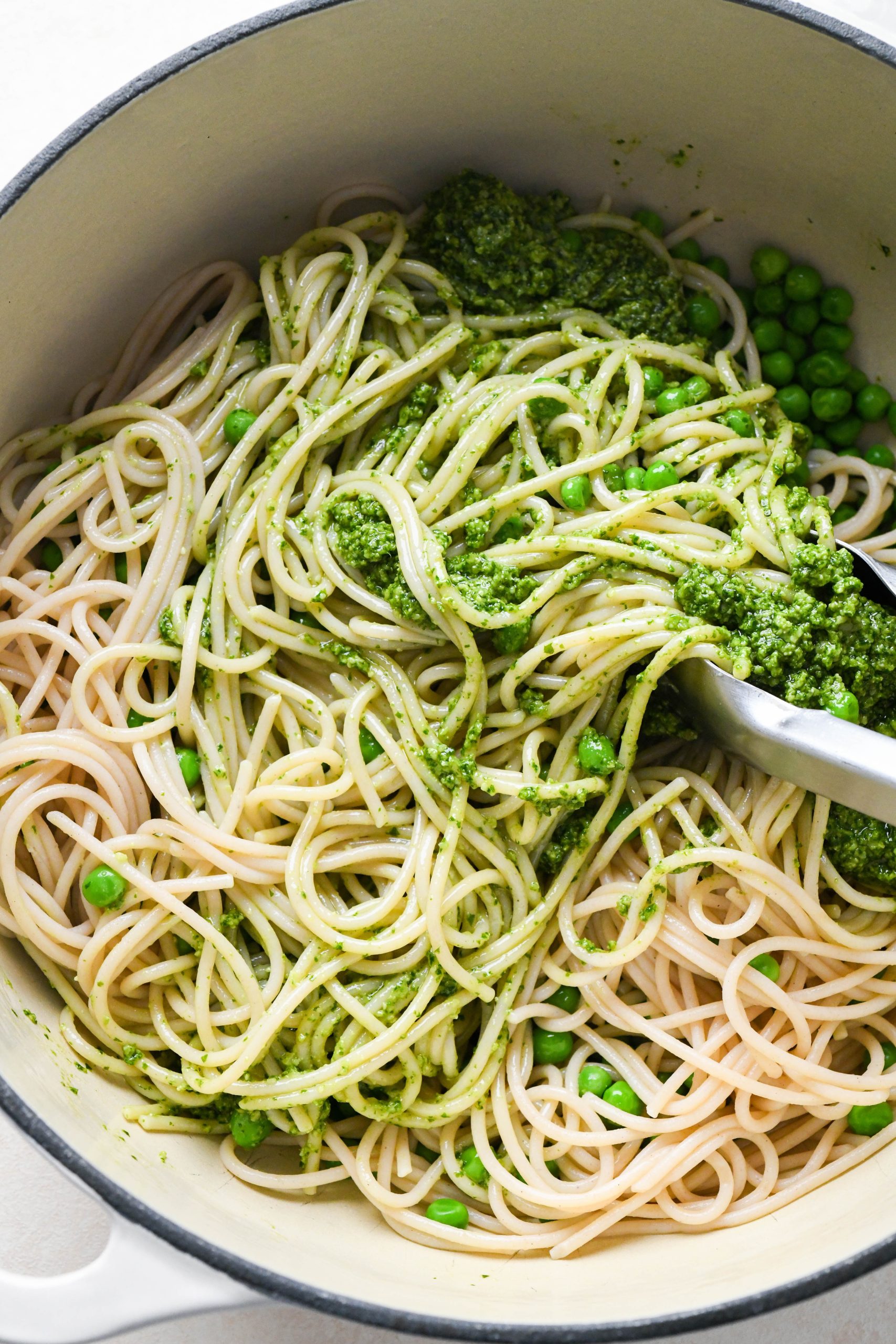 How to make easy pesto pasta: Tossing pasta together with sauce.