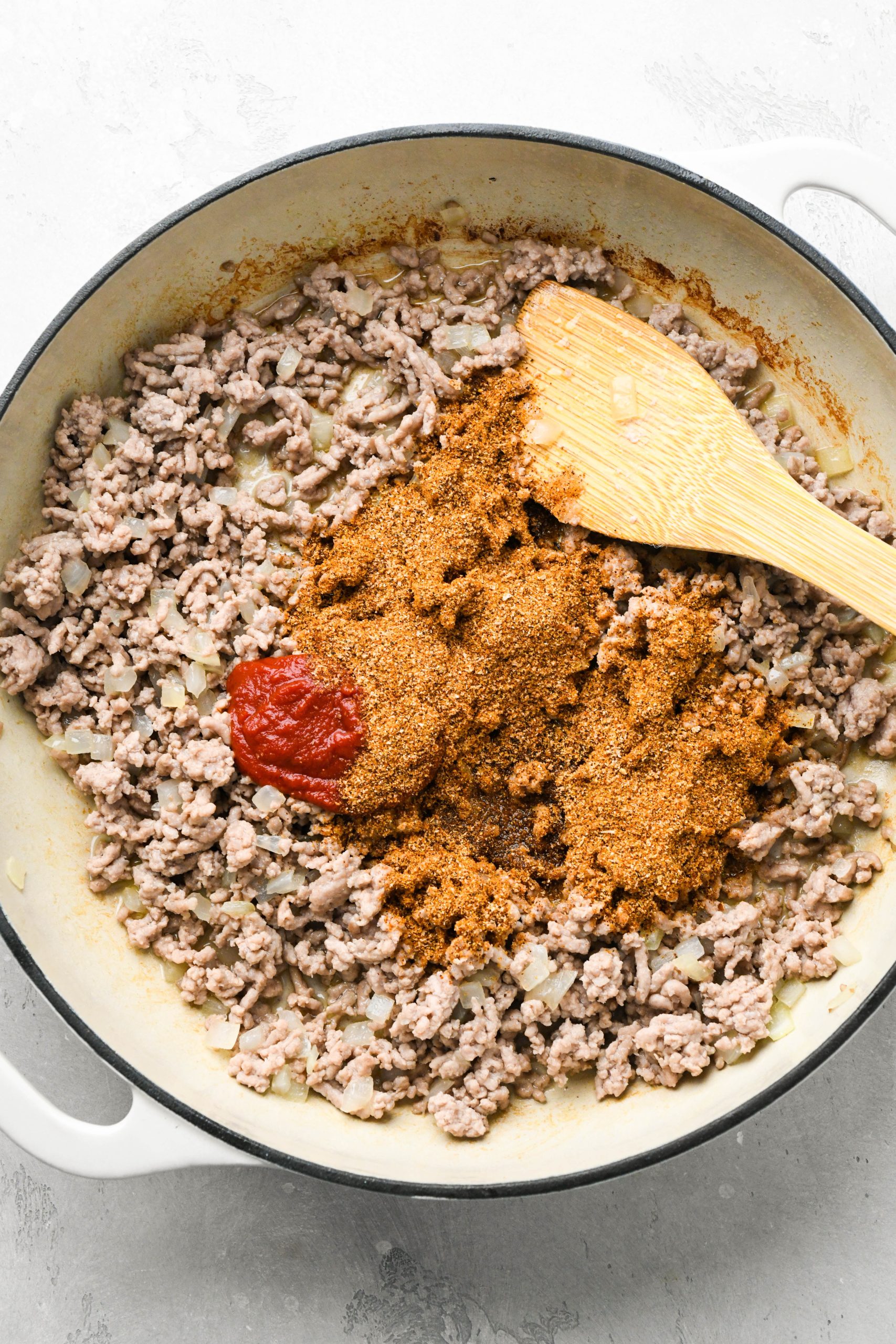 How to make ground pork tacos with creamy slaw: Ground pork in a skillet with spices and tomato paste. 