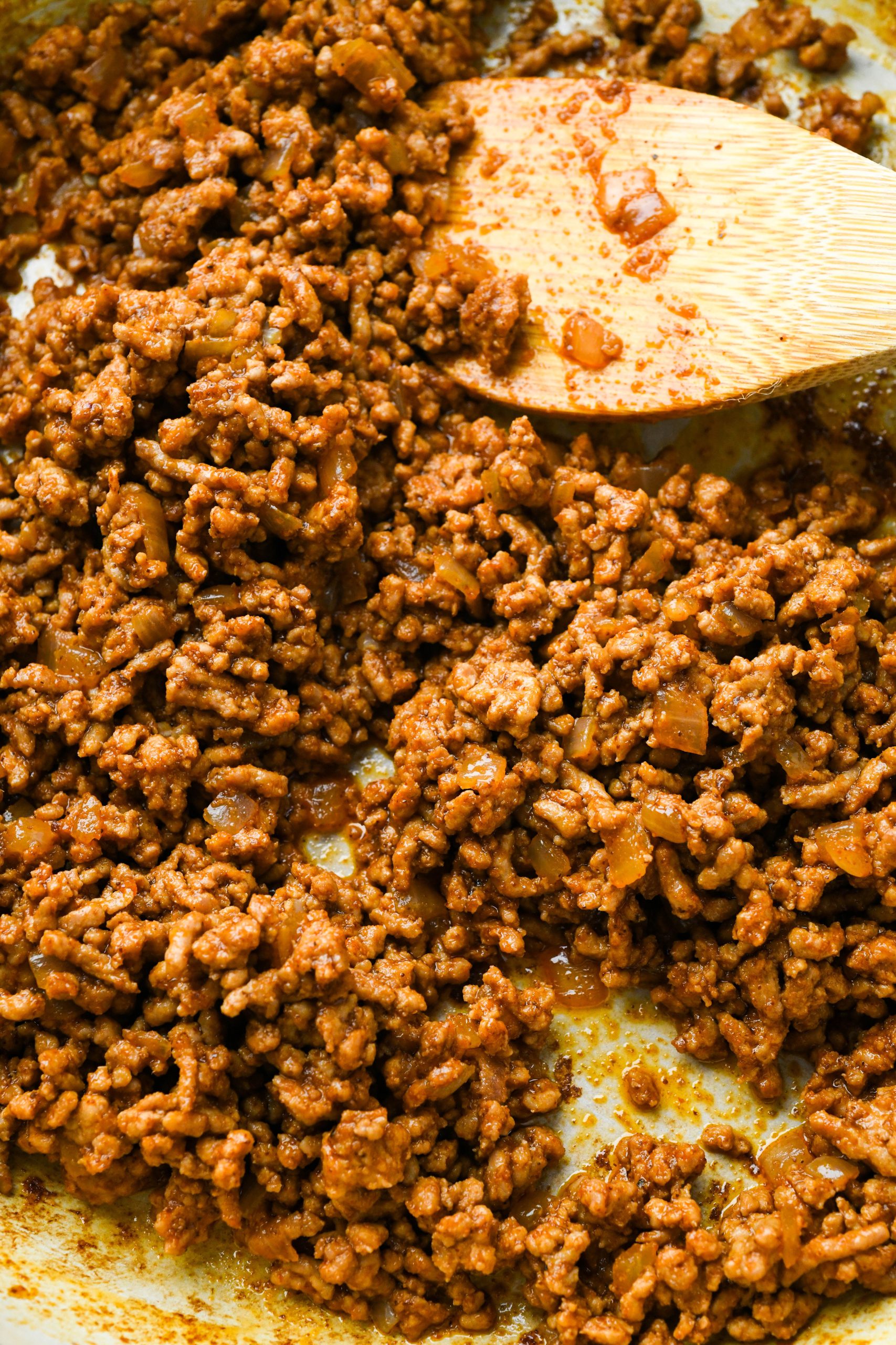 How to make ground pork tacos with creamy slaw: Close up of ground pork in a skillet cooked with spices.