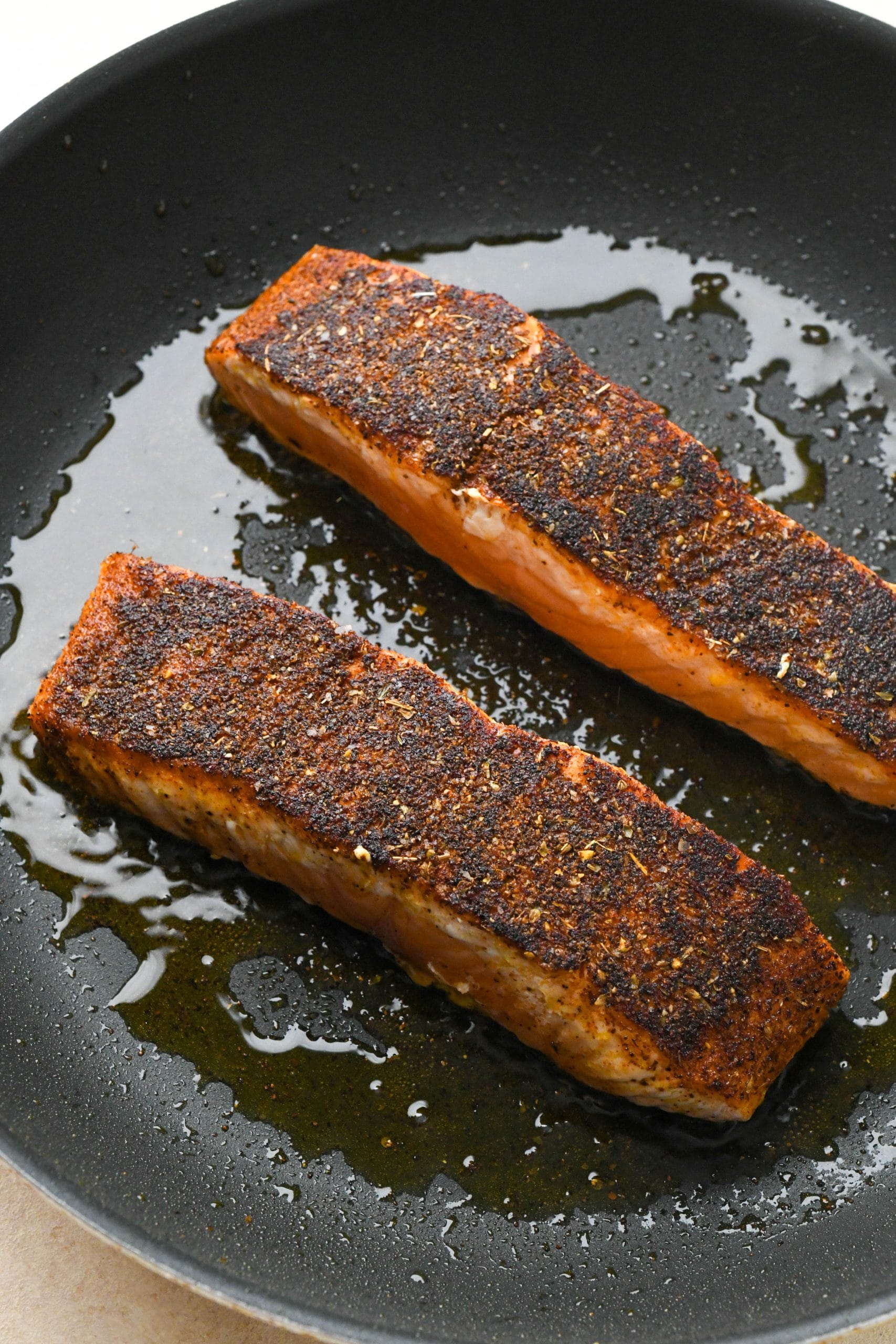 Salmon filets seared on the flesh side in a small skillet.
