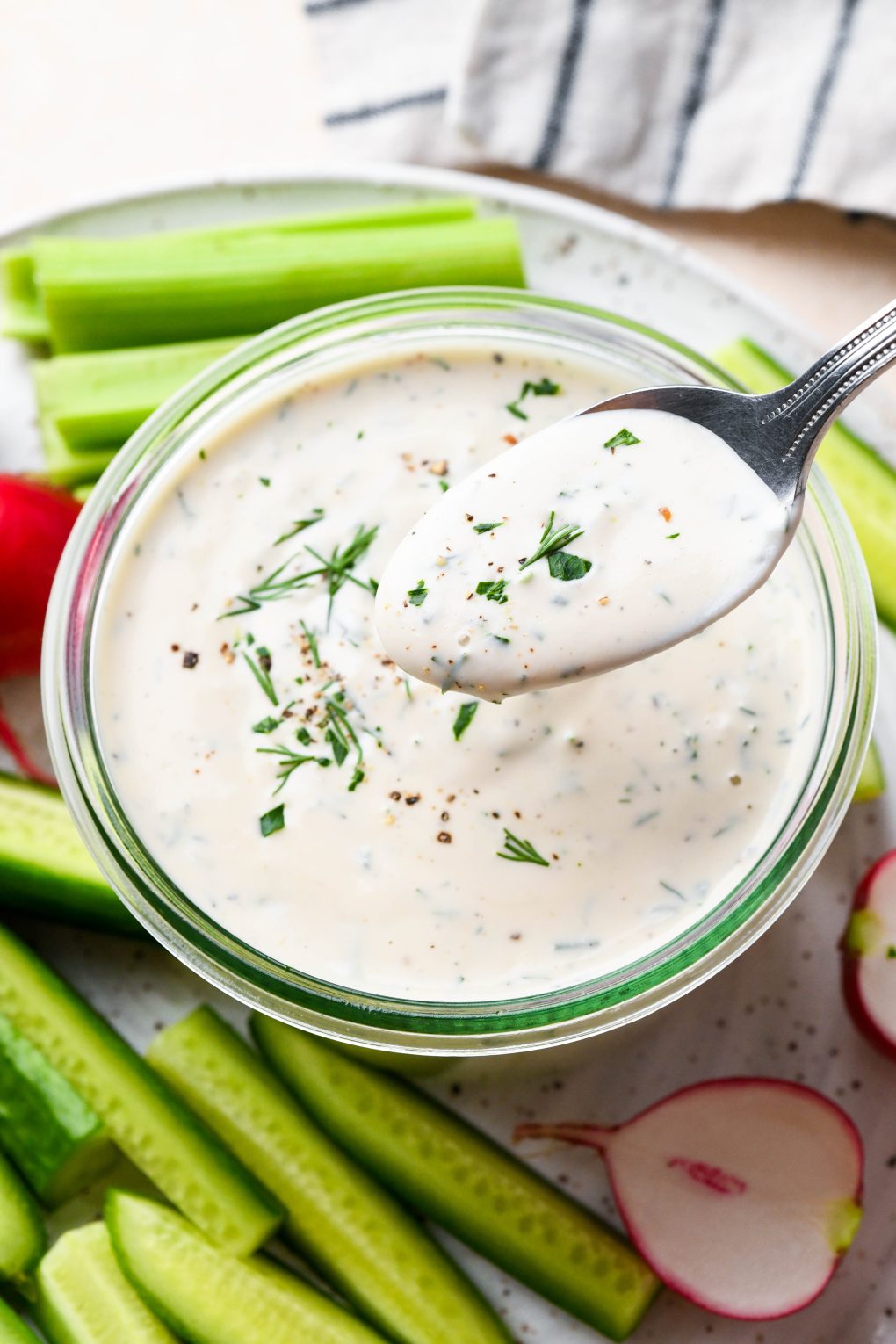 Vegan ranch in a small glass jar with a spoon lifting some of the dressing out to show the creamy texture.