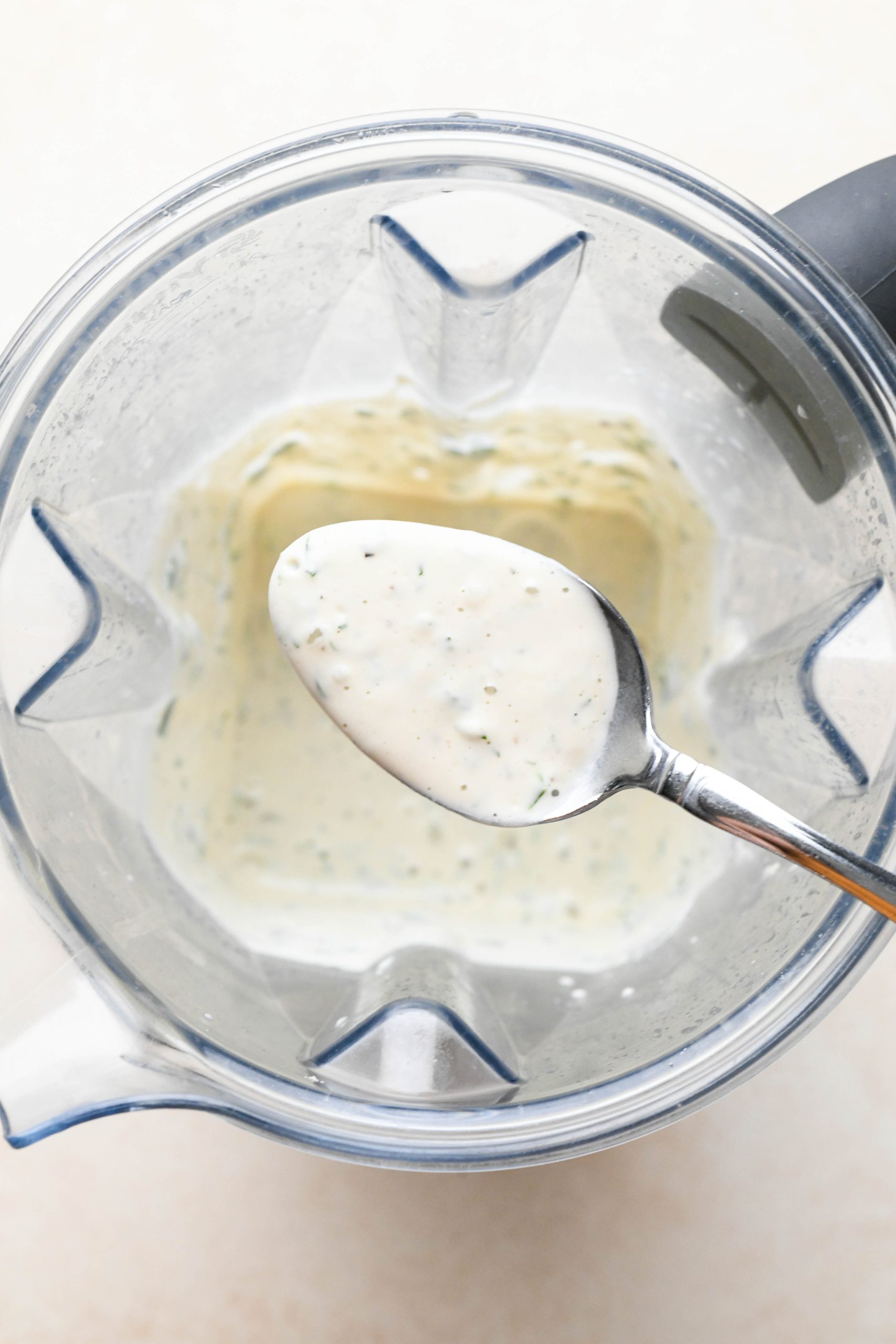 How to make vegan ranch dressing: Herbs and pepper pulsed into blended cashews in blender container.