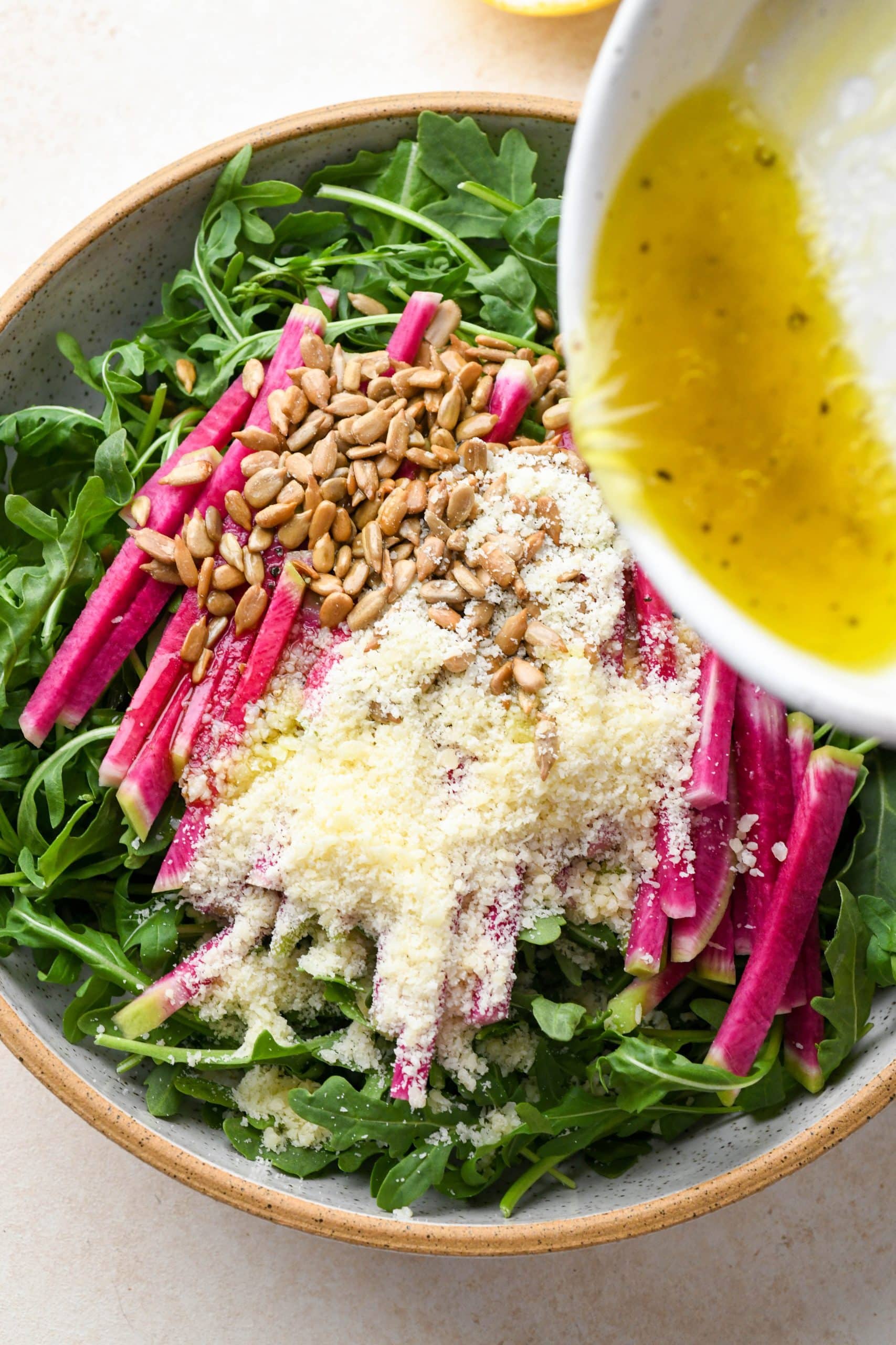 How to make Simple Arugula Salad: Pouring dressing over the salad.