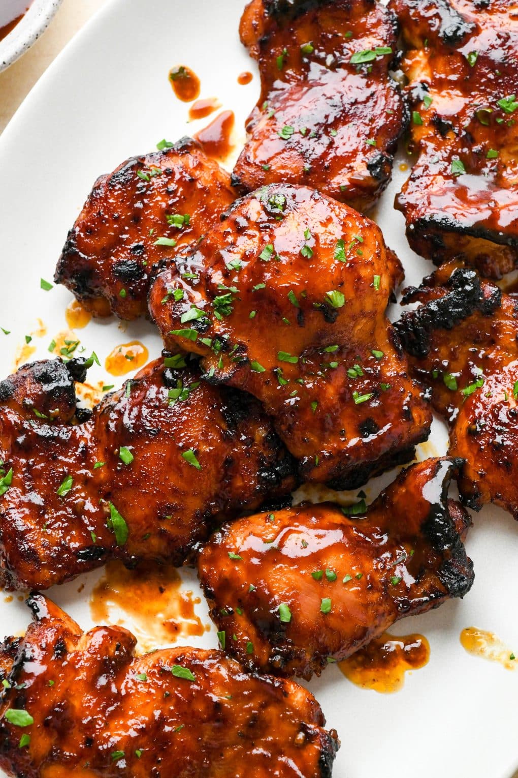 Baked bbq chicken thighs on a large white oval platter.
